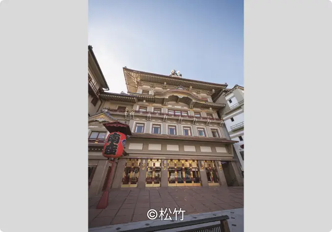 The iconic traditional multi-tiered facade of the Minamiza Kabuki Theatre in Kyoto, viewed from below, with a prominent red paper lantern at the entrance.