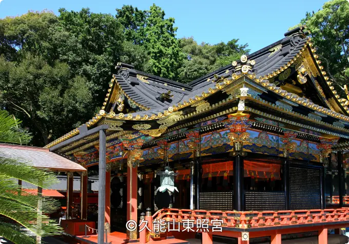 Close-up of the highly ornate, black, red, and gold Gongen-style architecture of a Kunozan Tōshō-gū hall on a sunny day.
