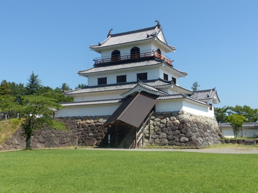Shiroishi Castle main keep and stone foundation under a clear sky.