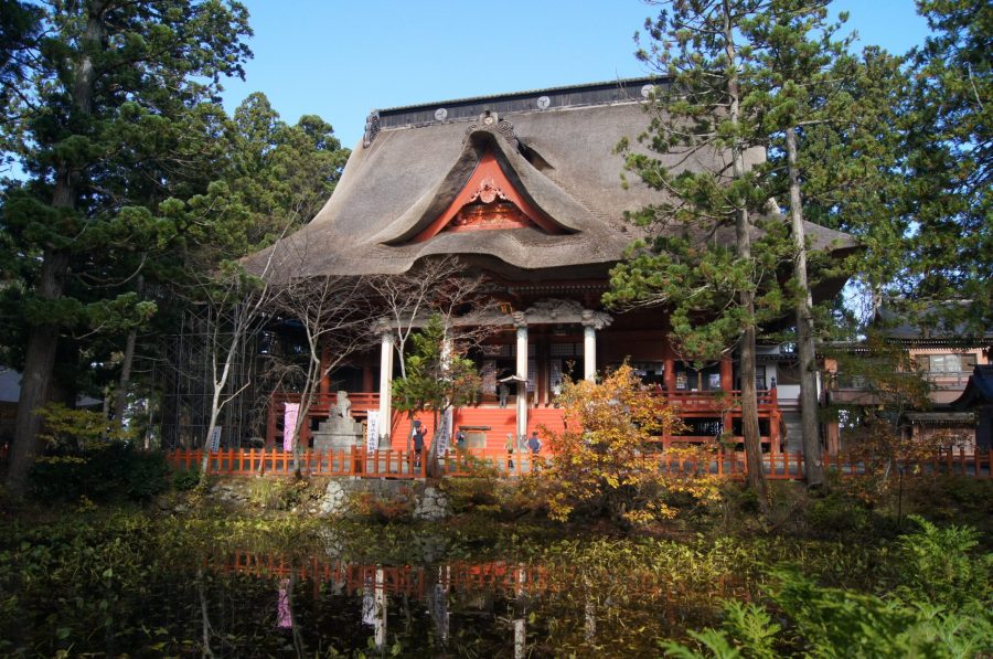 The Sanjin Gosai-den main shrine on Mt. Haguro with its large thatched roof, seen across a reflective pond.