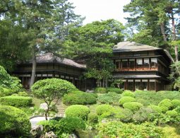 A traditional two-story Seienkaku villa with a tiled roof, surrounded by a lush Japanese garden.