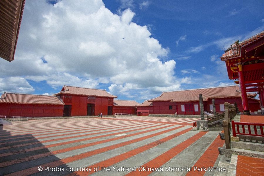 A wide view of the large courtyard (Una) in front of the main buildings of Shuri Castle, showing the distinct red and white striped paving.
