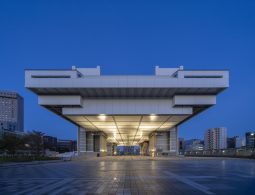 The monumental Edo-Tokyo Museum building at dusk, viewed head-on from the plaza below, illuminated from underneath.