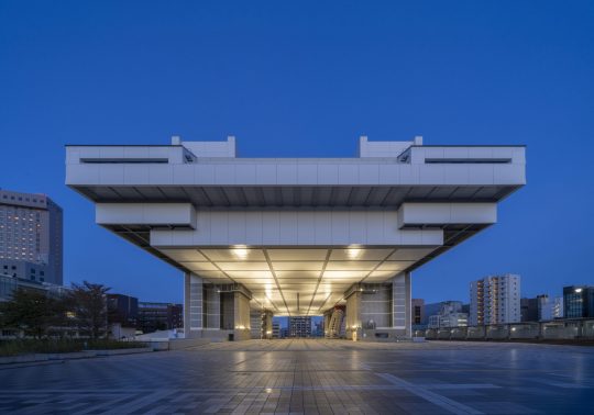 The monumental Edo-Tokyo Museum building at dusk, viewed head-on from the plaza below, illuminated from underneath.