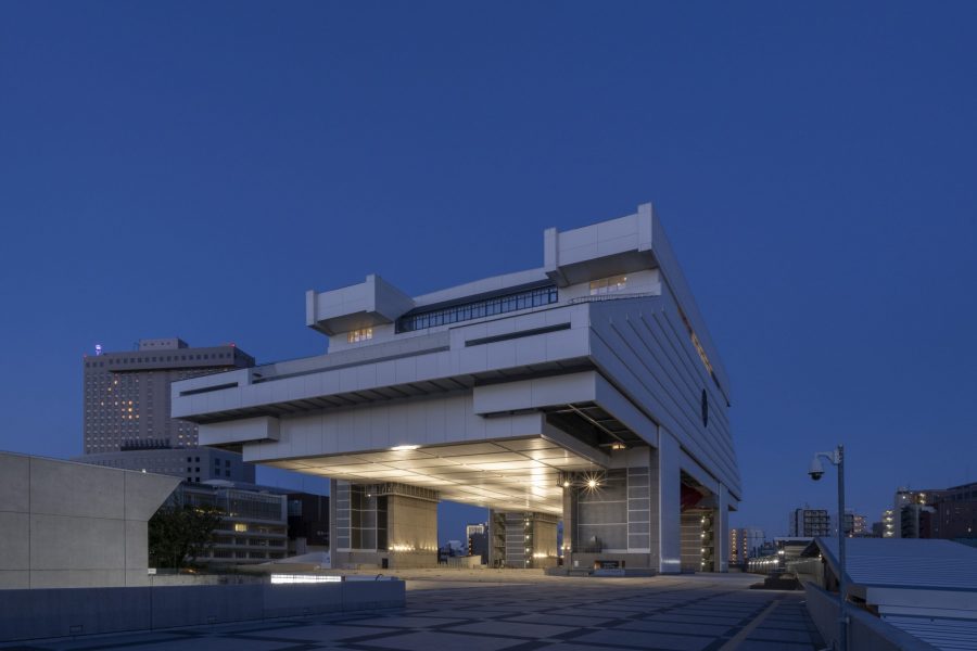 Angled view of the massive, cantilevered Edo-Tokyo Museum building lit up at night against a dark blue sky.