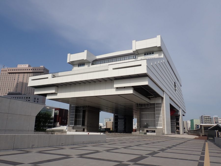 The white, elevated structure of the Edo-Tokyo Museum on a sunny day, resembling an ancient warehouse or a bridge, against a blue sky.