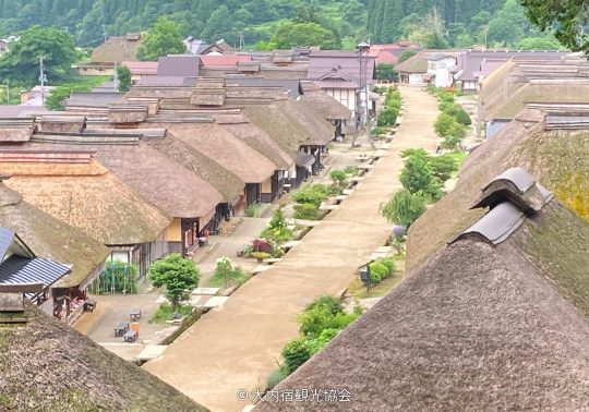 Overhead view of the main street of Ouchi-juku Post Town, lined with traditional thatched-roof houses.