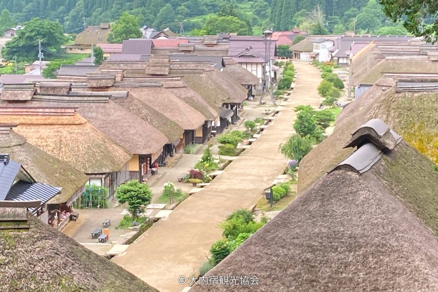 Overhead view of the main street of Ouchi-juku Post Town, lined with traditional thatched-roof houses.