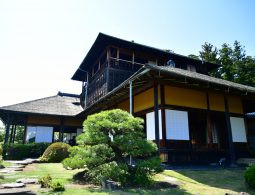 Close-up, low-angle view of the traditional, two-story Kobuntei building and a large sculpted pine tree.