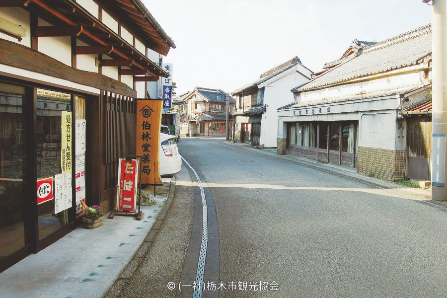 A historic streetscape in Kaeimon-cho with traditional white-walled and dark wood merchant buildings.