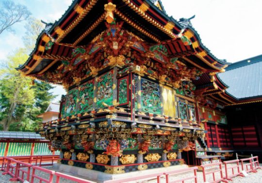 Close-up of a highly ornate temple building featuring vivid, detailed carvings, gold accents, and a tiered roof (Gongen-style architecture).