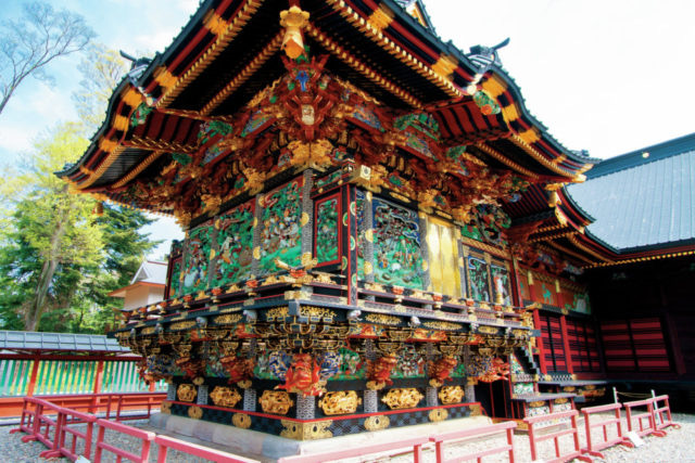 Close-up of a highly ornate temple building featuring vivid, detailed carvings, gold accents, and a tiered roof (Gongen-style architecture).