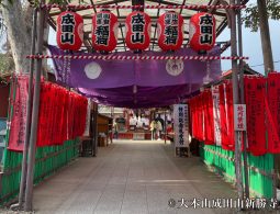 An entrance gate structure adorned with five large red paper lanterns and numerous red banners.