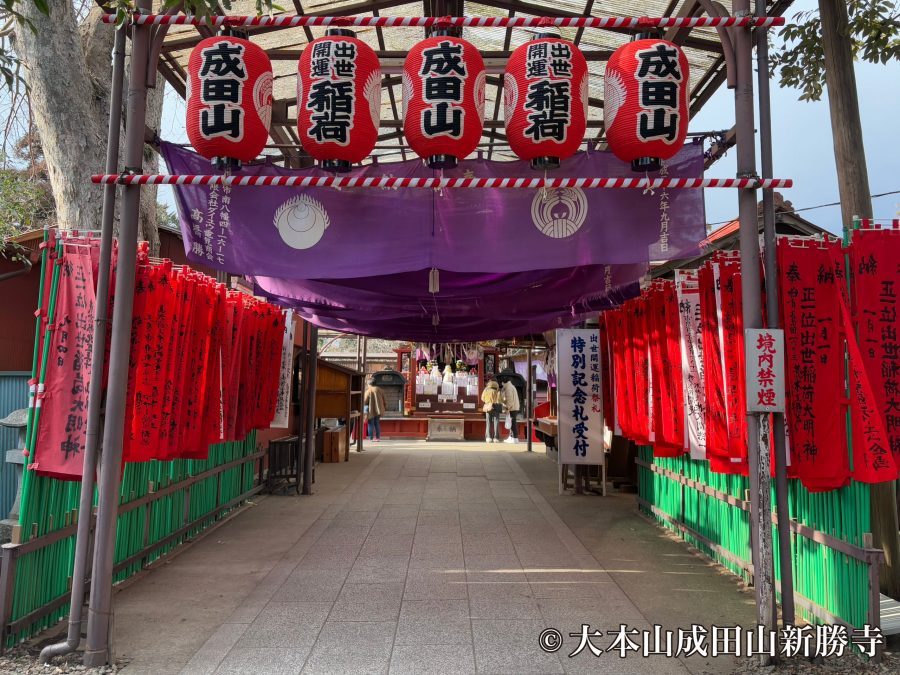 An entrance gate structure adorned with five large red paper lanterns and numerous red banners.