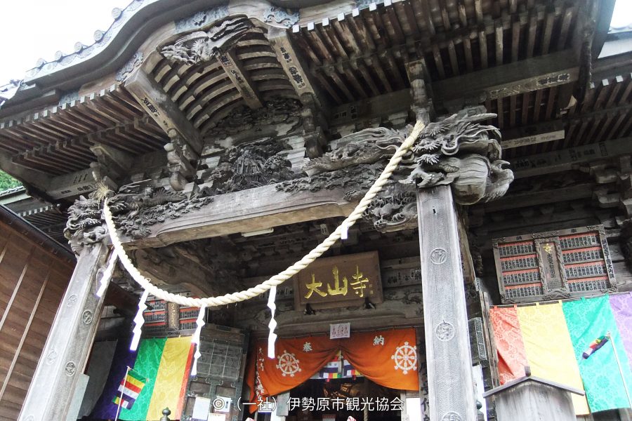 The richly carved wooden entrance gate of Oyama-dera Temple, with ropes and colorful flags.