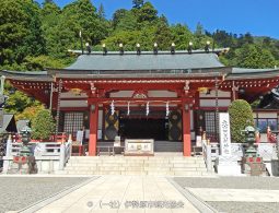 The red and white main hall of Oyama Afuri Shrine at the top of a stone staircase.