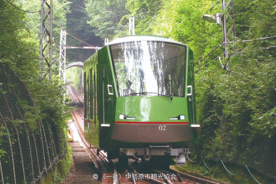 The Oyama Cable Car ascending the steep mountain track through the green forest.