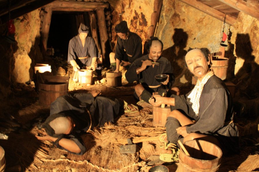 Diorama depicting Edo-period miners resting in a narrow, dimly lit mine shaft at Sado Gold Mine, showing their difficult working conditions.