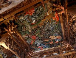 Detailed view of a multi-layered ceiling carving, including a tiger and a dragon, with original paint colors still visible.