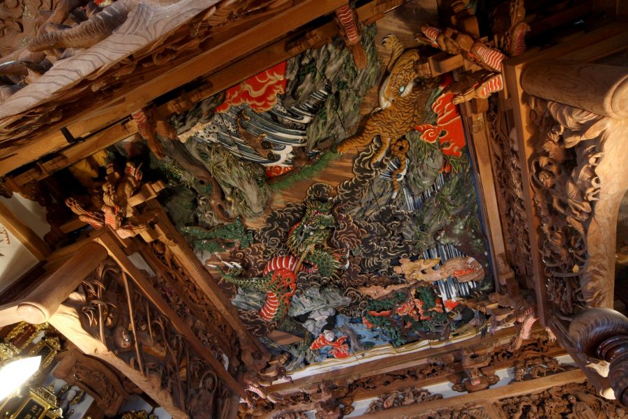 Detailed view of a multi-layered ceiling carving, including a tiger and a dragon, with original paint colors still visible.
