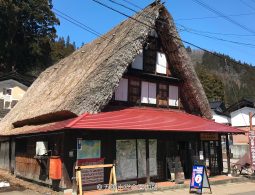 A traditional Gassho-zukuri house modified with a red tiled roof over the lower floor to serve as a tourist information center.