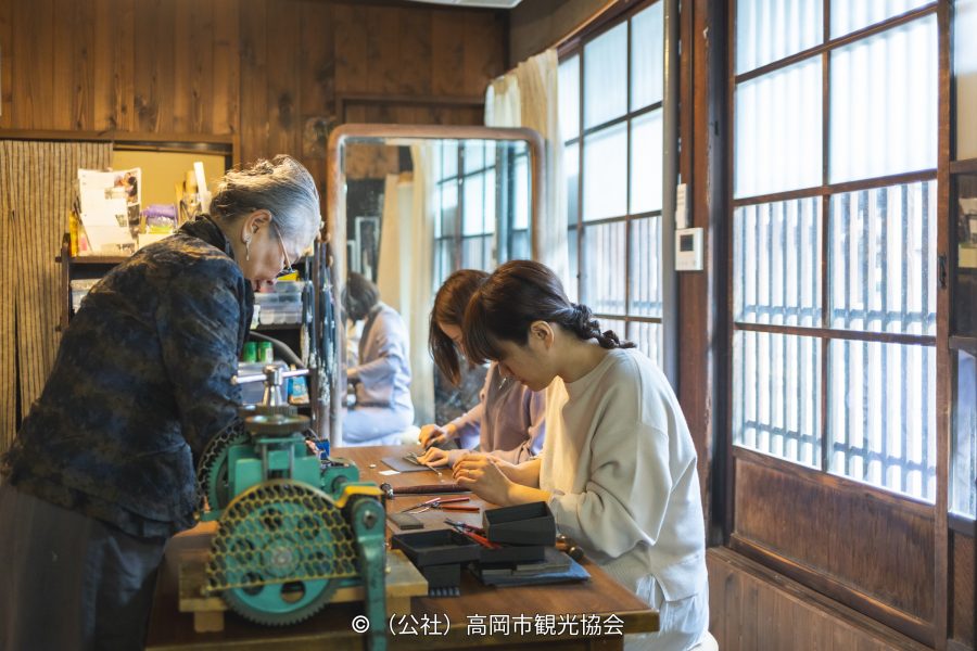 People engaging in a traditional metalworking or crafting experience inside a wooden workshop.