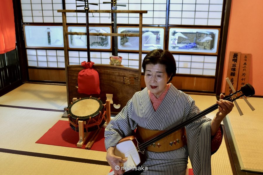 Traditional wooden townhouses (machiya) with open facades lining a quiet street in Mikuni Minato.