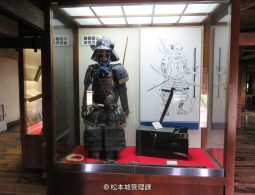 A full set of black samurai armor displayed inside a glass case within the castle museum.