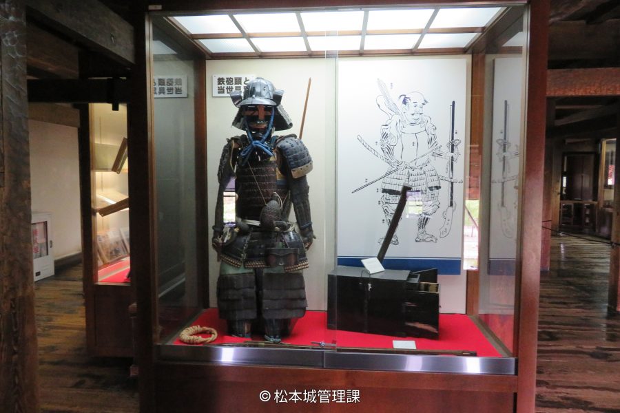 A full set of black samurai armor displayed inside a glass case within the castle museum.