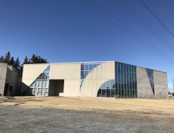The modern, concrete and glass exterior of the Japan Ukiyo-e Museum under a clear blue sky.