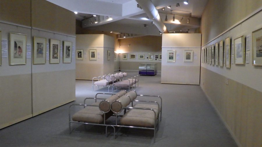 The interior of the Ukiyo-e Museum exhibition hall with rows of framed prints on the walls and low benches.