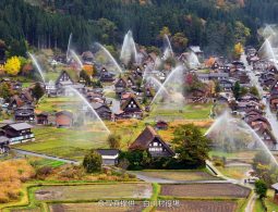 Overhead view of the Gassho-zukuri village during a large-scale water-discharge fire drill in autumn.