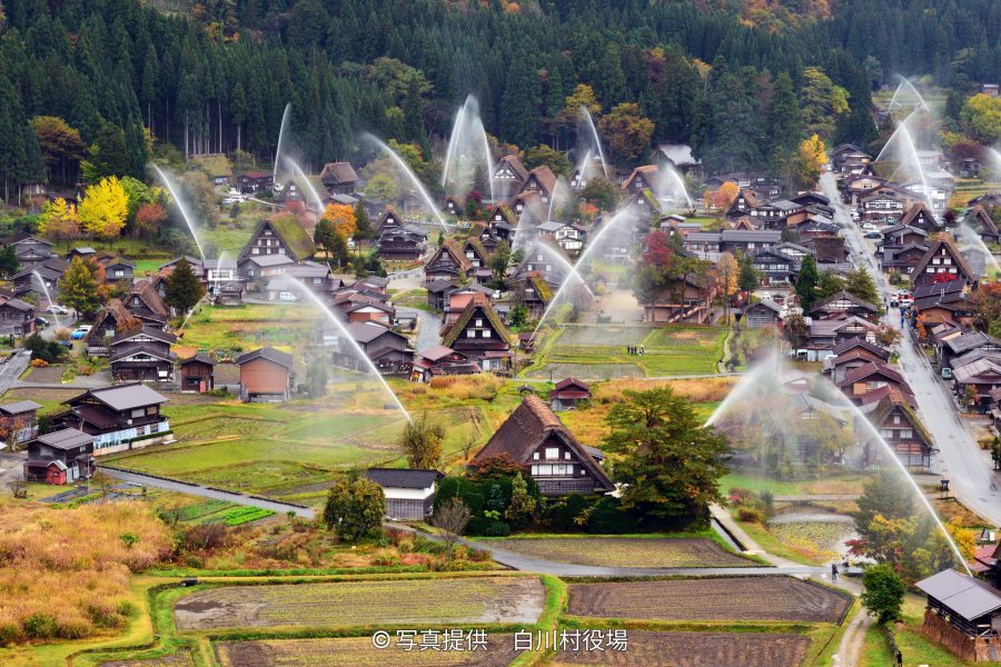 Overhead view of the Gassho-zukuri village during a large-scale water-discharge fire drill in autumn.