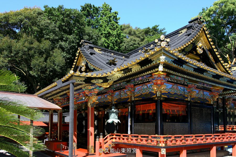 Close-up of the highly ornate, black, red, and gold Gongen-style architecture of a Kunozan Tōshō-gū hall on a sunny day.