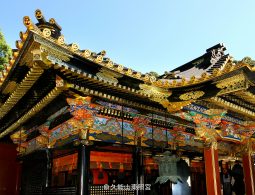 Detailed view of the eaves, layered black and gold roof, and colorful carved transoms of the Kunozan Tōshō-gū complex.