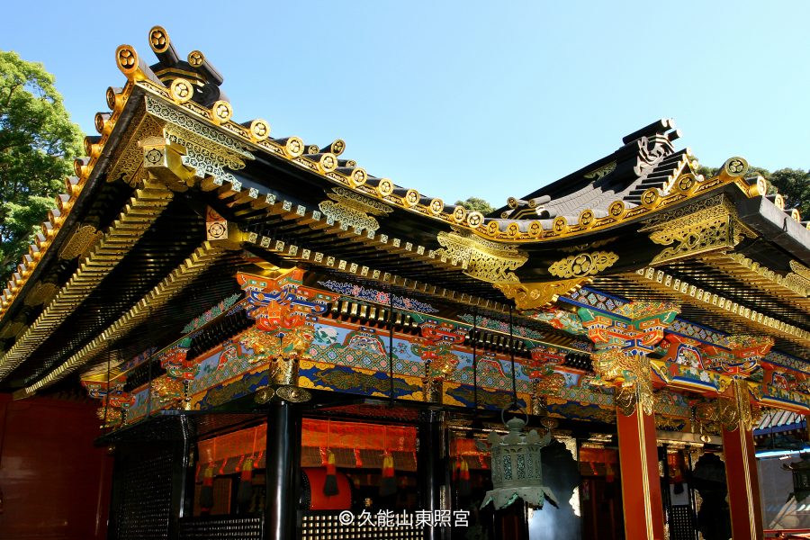 Detailed view of the eaves, layered black and gold roof, and colorful carved transoms of the Kunozan Tōshō-gū complex.