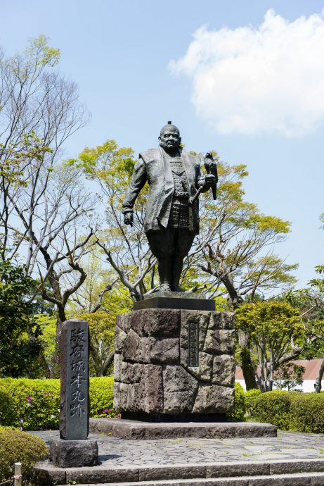 A statue of Tokugawa Ieyasu holding a hawk (falconry posture) on a stone pedestal in Sunpu Castle Park.