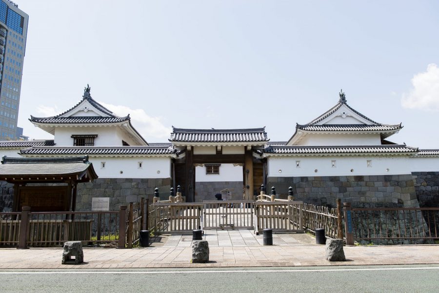 The reconstructed gate and surrounding turreted walls of Sunpu Castle Park, built with white plaster above a stone foundation.