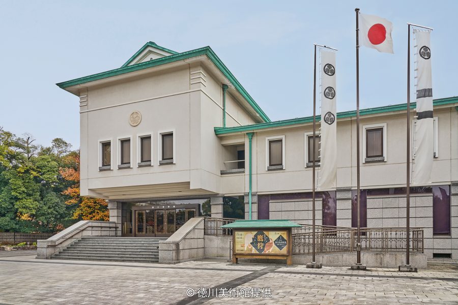 The exterior of the Tokugawa Art Museum, an Imperial Crown style building with multiple flags bearing the Tokugawa crest.