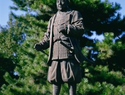 A bronze statue of Tokugawa Ieyasu in samurai attire (yoroi-hitatare) standing in the castle park.