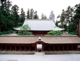 The Konpon Chudo main hall of Enryaku-ji Temple, featuring a large roof and outer corridor structure, surrounded by dense cedar forest.