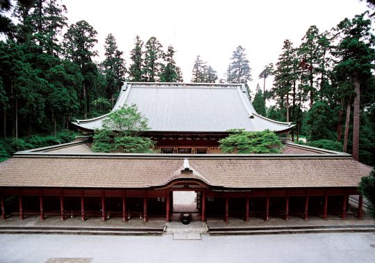 The Konpon Chudo main hall of Enryaku-ji Temple, featuring a large roof and outer corridor structure, surrounded by dense cedar forest.