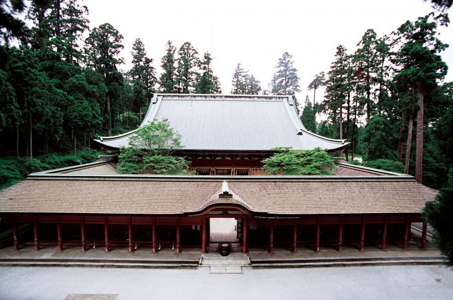 The Konpon Chudo main hall of Enryaku-ji Temple, featuring a large roof and outer corridor structure, surrounded by dense cedar forest.