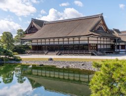 The Oikeniwa Garden at Kyoto Imperial Palace, viewed over the pond with reflections of the traditional building and surrounding pine trees.