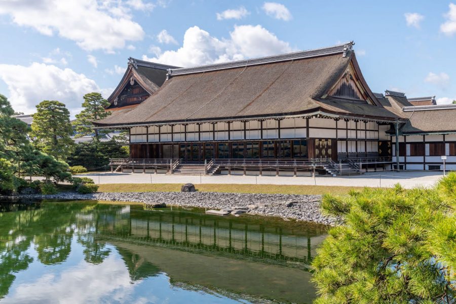 The Oikeniwa Garden at Kyoto Imperial Palace, viewed over the pond with reflections of the traditional building and surrounding pine trees.