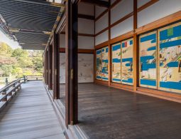 Long wooden veranda of the Kogosho at Kyoto Imperial Palace, facing the garden. Interior sliding doors are visible on the right, decorated with landscapes featuring vibrant blue sections.