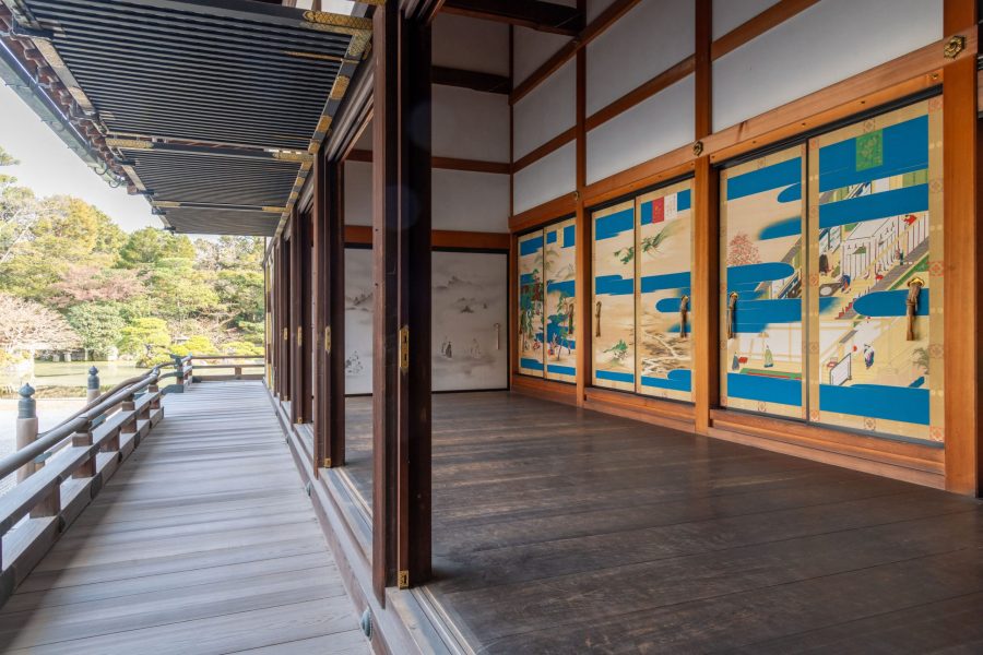 Long wooden veranda of the Kogosho at Kyoto Imperial Palace, facing the garden. Interior sliding doors are visible on the right, decorated with landscapes featuring vibrant blue sections.