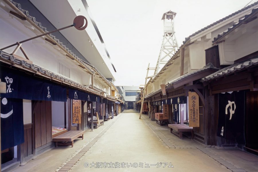 The indoor recreated Edo period streetscape exhibit at the Osaka Museum of Housing and Living, lined with traditional wooden machiya buildings and a fire watch tower.