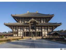 The massive Daibutsuden hall of Todai-ji Temple under a bright blue sky, with a wide, open plaza in the foreground.