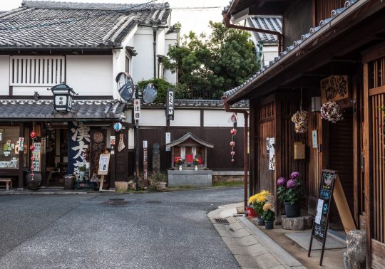 A street corner in Naramachi showing preserved merchant houses and a small wayside shrine (hokora).